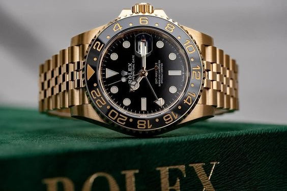 Gold and black Rolex watch on a green surface