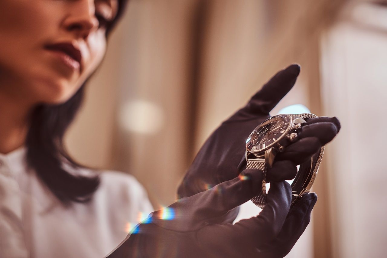Person wearing black gloves holding a watch with a blurred background