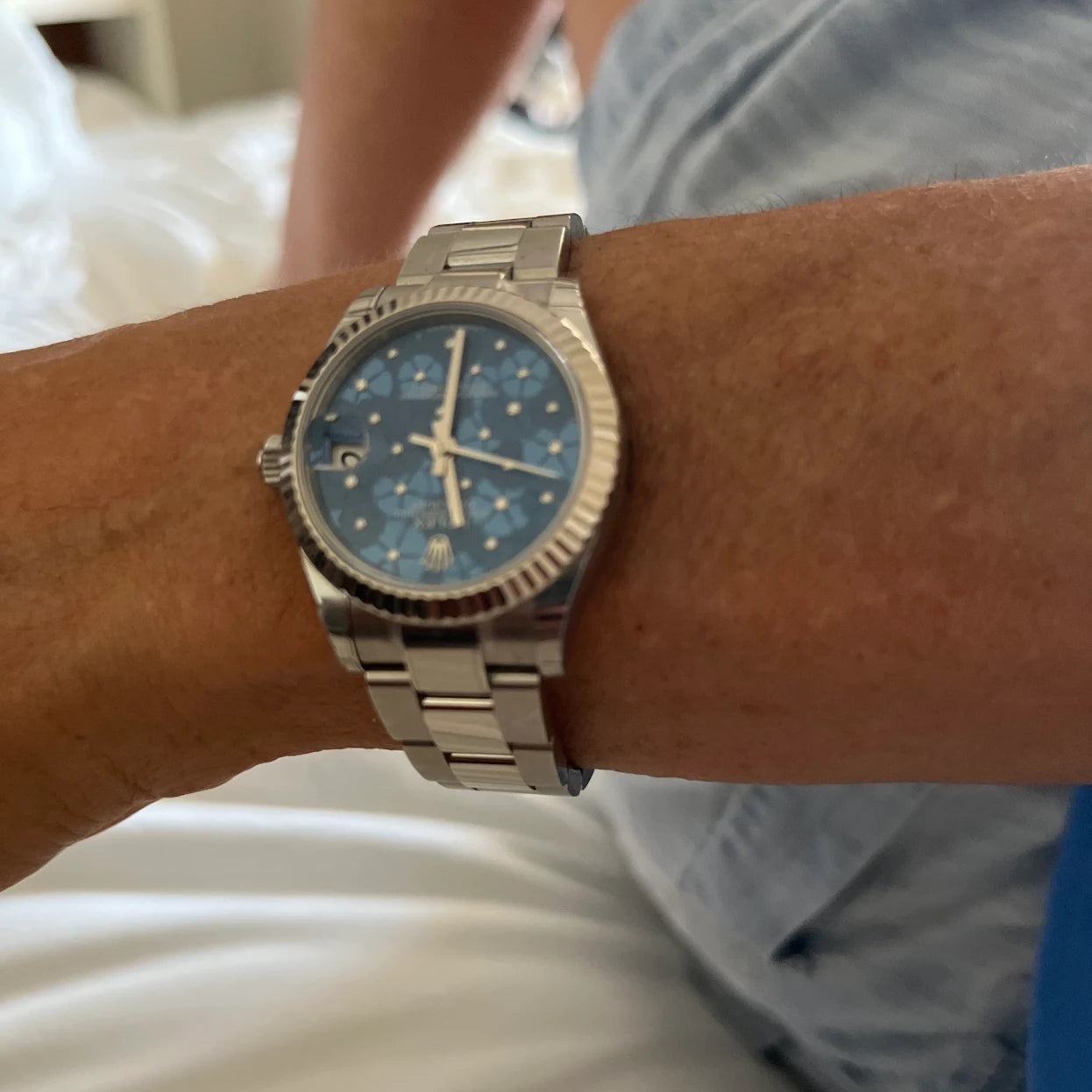 Close-up of a wrist wearing a silver watch with a blue face.