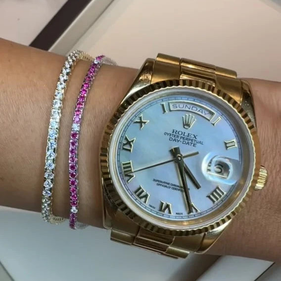 Gold Rolex watch on a wrist with two bracelets