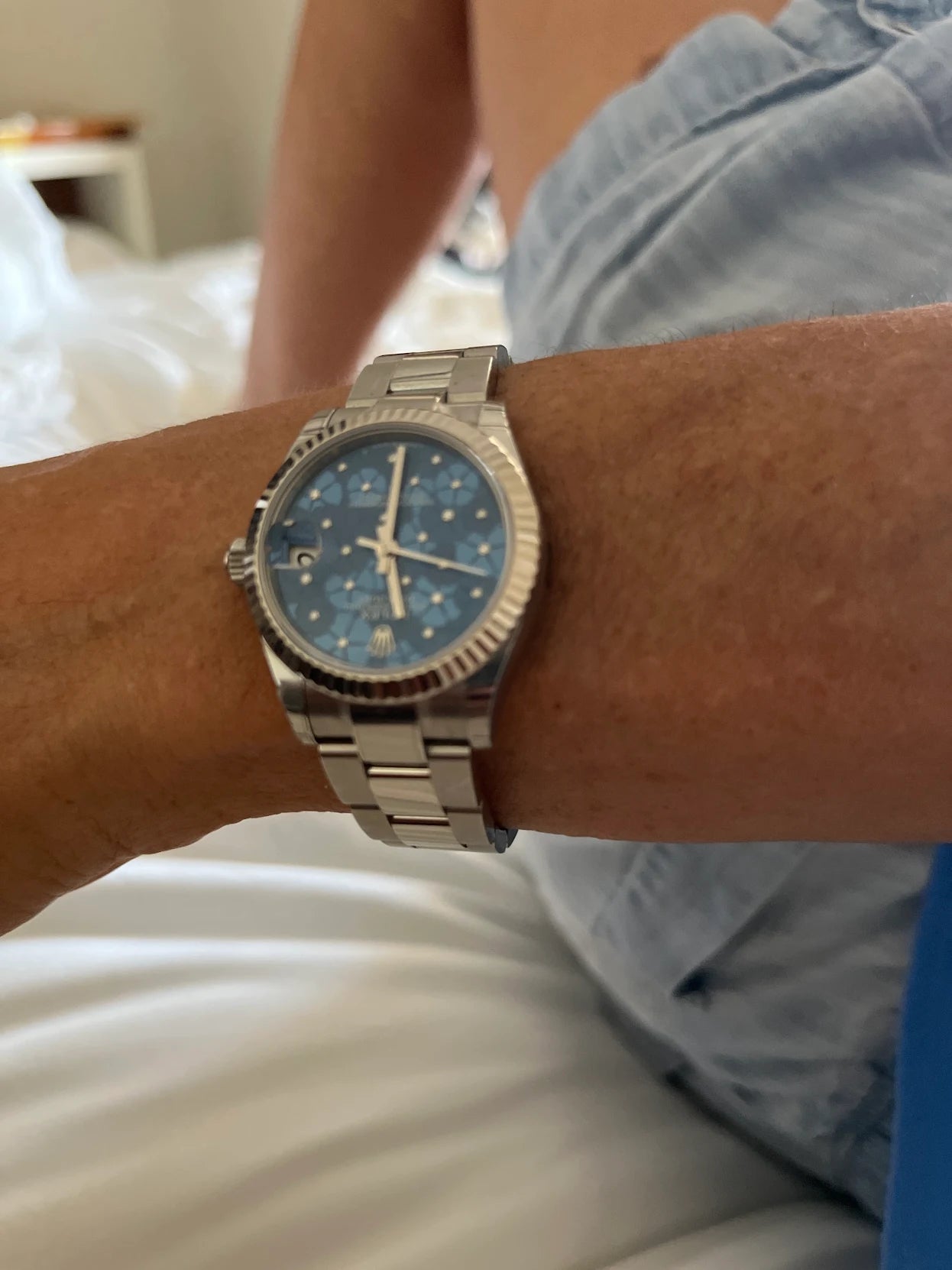 Close-up of a wrist wearing a silver watch with a blue face.