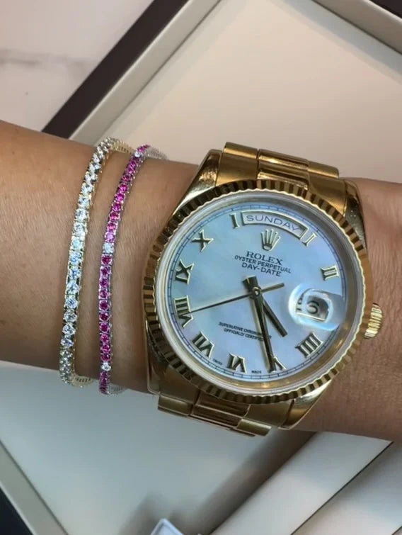 Gold Rolex watch on a wrist with two bracelets